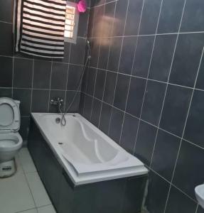 a bathroom with a bath tub and a toilet at Plistbooking 3 Bedroom Duplex, City View Estate in Pakuro