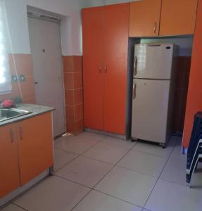 a kitchen with a white refrigerator and orange cabinets at Plistbooking 3 Bedroom Duplex, City View Estate in Pakuro