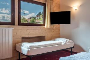 a room with a tv on the wall and a window at Hotel Residence Gardena Saslong in Santa Cristina in Val Gardena