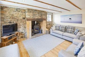 sala de estar con pared de piedra y chimenea en Host & Stay - Eden Cottage, en Holy Island