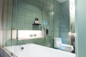a green tiled bathroom with a tub and a toilet at karaarom hotel in Bangkok