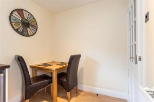 a dining room table with chairs and a clock on the wall at Chapel Street 42B First floor 1-bedroom apartment, Aberdeen city center in Aberdeen