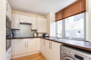 a kitchen with white cabinets and a sink and a window at Chapel Street 42B First floor 1-bedroom apartment, Aberdeen city center in Aberdeen
