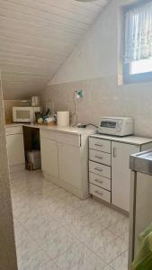 uma pequena cozinha com armários brancos e um micro-ondas em Sunny view Apartman em Barbat na Rabu