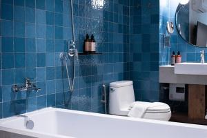 a blue tiled bathroom with a toilet and a bath tub at karaarom hotel in Bangkok