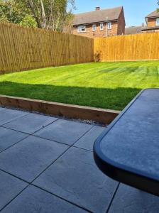 a backyard with a fence and a lawn at lovely4 bedroom house close to Loughborough uni/M1 in Loughborough