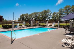 a swimming pool with lounge chairs and an umbrella at Quality Inn Southaven - Memphis South in Southaven