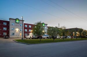 a parking lot in front of a building with green signs at Quality Inn & Suites in Whitecourt