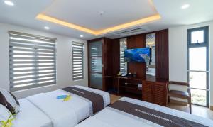 a bedroom with two beds and a desk and windows at Vương Quốc 3 Hotel in Quy Nhon