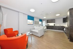 a living room with orange and white chairs and a kitchen at Cosy Apartments and Private Ensuite at Mill House in Edinburgh in Edinburgh