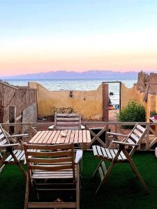une table et des chaises en bois avec l'océan en arrière-plan dans l'établissement Luna House Asala Beach, à Dahab
