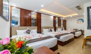 a hotel room with three beds and flowers at Vương Quốc 3 Hotel in Quy Nhon