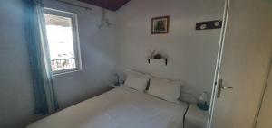 Apartmani Marijan Zavala في زافالا: غرفة نوم صغيرة بها سرير أبيض ونافذة