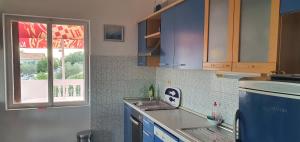 a kitchen with blue cabinets and a window at Apartmani Marijan Zavala in Zavala