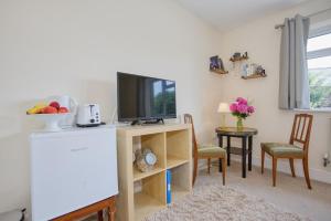 a living room with a television and a table with chairs at Old Orchard in Otterford