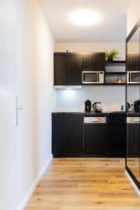 a kitchen with black cabinets and a wooden floor at Moderne Ferienunterkunft in ruhiger Lage und nur 7 Gehminuten vom Strand entfernt - hoher Schlafkomfort und Gartenzugang für die ideale Erholung an der Ostsee in Scharbeutz +22 photos