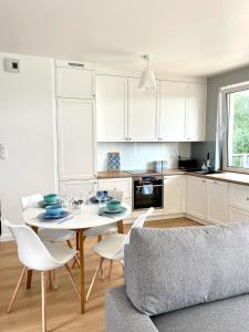kuchnia z białymi szafkami oraz stołem i krzesłami w obiekcie Blue Apartment w Kielcach