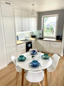cocina blanca con mesa blanca y sillas en Blue Apartment, en Kielce