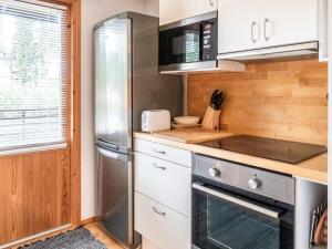 uma cozinha com armários brancos e um frigorífico de aço inoxidável em Holiday Home Kanervarinne by Interhome em Vuokatti