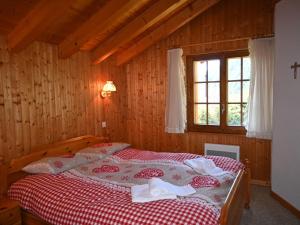 um quarto com uma cama com um cobertor vermelho e branco em Chalet Véronique by Interhome em Ovronnaz