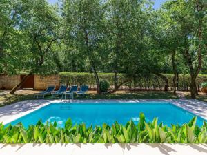 basen na podwórku z krzesłami i drzewami w obiekcie Holiday Home Villa Frleti by Interhome w mieście Umag