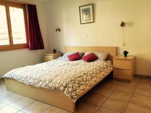 een slaapkamer met een bed met 2 rode kussens bij Apartment Alpine Retreat by Interhome in Adelboden