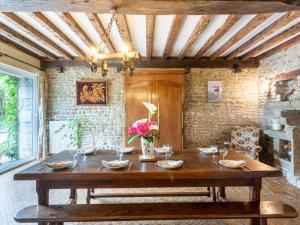 a dining room with a wooden table with flowers on it at Holiday Home Le bois bourdin by Interhome in Pontorson