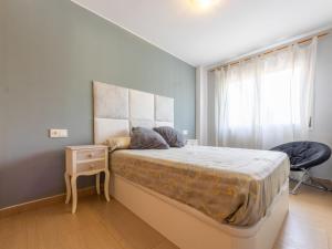 Un dormitorio con una cama grande y una silla. en Apartment Luxor by Interhome, en Torredembarra