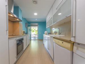 cocina grande con armarios blancos y paredes azules en Apartment Luxor by Interhome, en Torredembarra