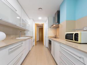Una cocina con gabinetes blancos y un microondas en la encimera. en Apartment Luxor by Interhome, en Torredembarra