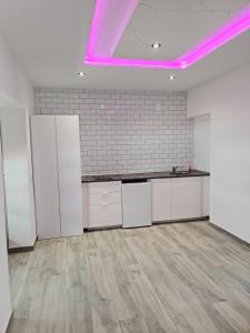 eine Küche mit weißen Schränken und rosafarbener Beleuchtung in der Unterkunft Apartamento Luxury Suite Huelva Zona Centro in Huelva