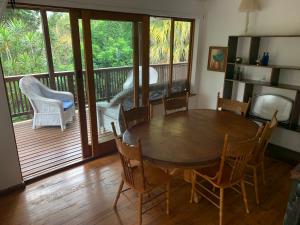 a dining room with a table and chairs and a balcony at Jackalberry Cottage in Lobamba