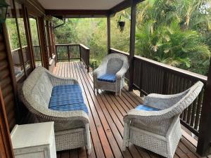 a porch with wicker chairs and a bench on it at Jackalberry Cottage in Lobamba
