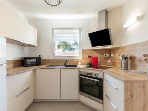 cocina con armarios blancos y TV en la pared en Holiday Home Vinci by Interhome, en Royan