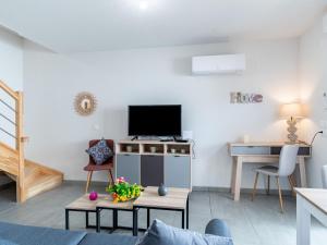 a living room with a tv and a desk at Apartment SC H01 by Interhome in Mimizan +26 photos