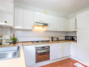 una cocina con armarios blancos y fregadero en Holiday Home Cantamar by Interhome, en Torredembarra
