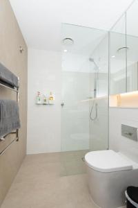 a white bathroom with a shower and a toilet at MetaWise Sydney CBD Luxury City view 2BED Apartment in Sydney