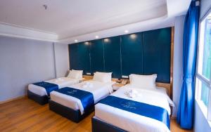 three beds in a room with blue walls at Sapphire Hotel Silom Bangkok in Bangkok