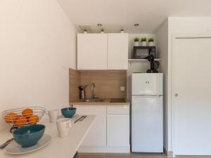 kuchnia z białymi szafkami i białą lodówką w obiekcie Studio Les Aigues Marines-63 by Interhome w mieście Saint-Cyr-sur-Mer +10 zdjęć