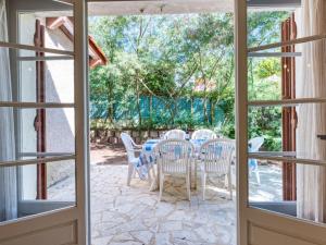 otwarte drzwi na patio ze stołem i krzesłami w obiekcie Holiday Home Dominique by Interhome w mieście Lacanau-Océan