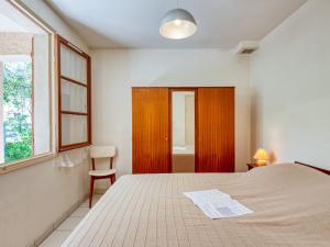 sypialnia z łóżkiem, krzesłem i oknem w obiekcie Holiday Home Dominique by Interhome w mieście Lacanau-Océan