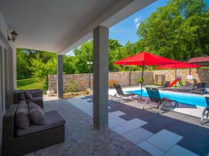 a patio with a pool and red umbrellas at Holiday Home Olivia by Interhome in Bribir