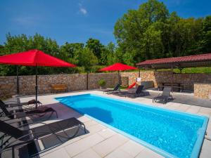 a swimming pool with two umbrellas and chairs and a pool at Holiday Home Olivia by Interhome in Bribir +31 photos