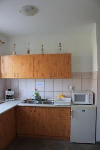 cocina con armarios de madera, fregadero y microondas en Peregi Vendégház en Mezőhegyes