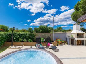a backyard pool with a hot tub and a patio with chairs at Holiday Home Laura in Pula