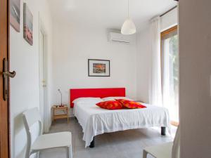 Apartment More e Lamponi by Interhome في Avane: غرفة نوم عليها سرير ومخدات حمراء
