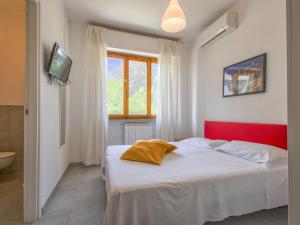 Apartment More e Lamponi by Interhome في Avane: سرير أبيض مع اللوح الأمامي الأحمر في غرفة النوم
