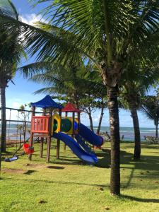 einen Spielplatz mit Rutsche neben einer Palme in der Unterkunft Paraiso dos Corais in Guarajuba