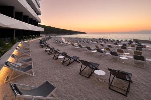 a row of chairs and tables on a beach at Grand Hotel View in Postira