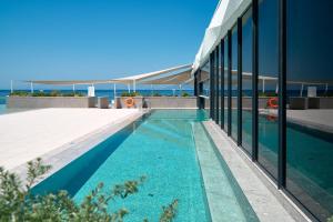 a swimming pool next to a building with glass windows at Grand Hotel View in Postira
